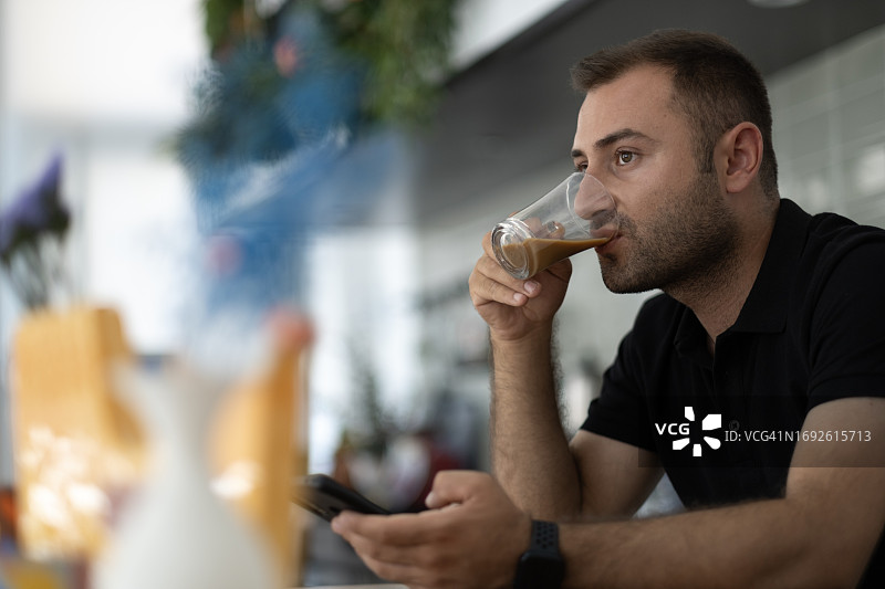 年轻男艺术家围着围裙在使用手机图片素材