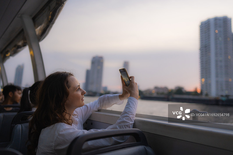 女子乘船在湄南河上旅行，拍摄曼谷日落美景图片素材