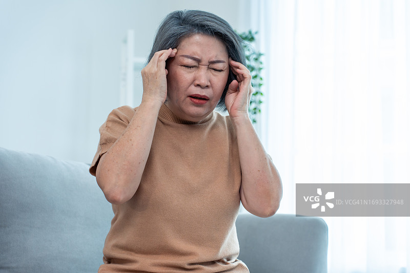 独自坐在客厅里的亚洲老年妇女，因生活问题感到悲伤和沮丧，思考着债务、预算损失、破产图片素材