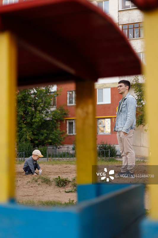 男孩在爸爸附近玩沙子图片素材