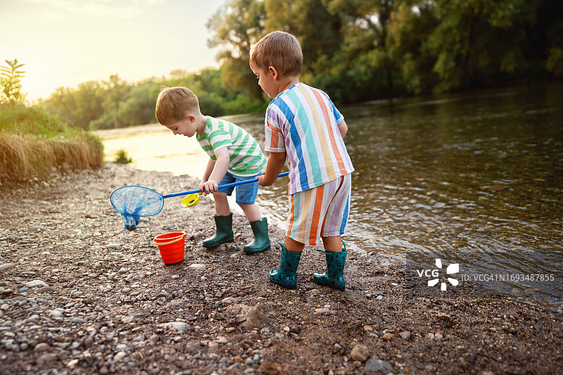 两个小男孩在河边享受无忧无虑的夏日时光图片素材