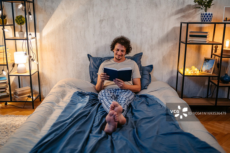 年轻人晚上在床上看书图片素材