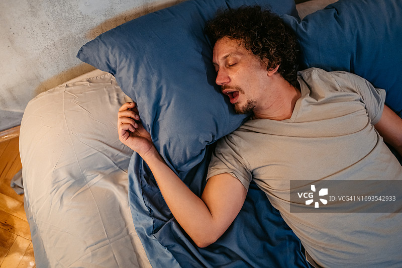 年轻男子晚上在床上打鼾图片素材