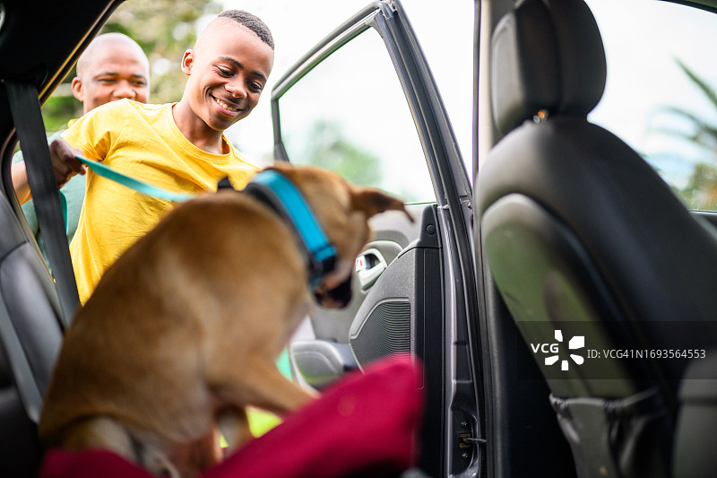快乐的青少年男孩和狗在车里准备开车兜风图片素材