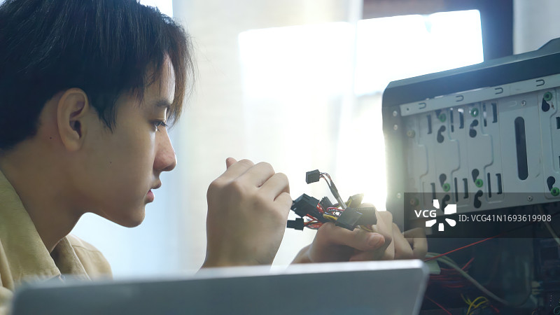 亚洲男童在课堂上学习修理电脑和电子板，大学工程电子教育图片素材
