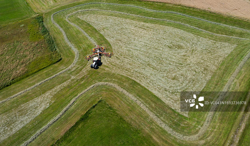奥地利萨尔茨堡州弗拉绍地区，拖拉机在田野里翻干草航拍图片素材