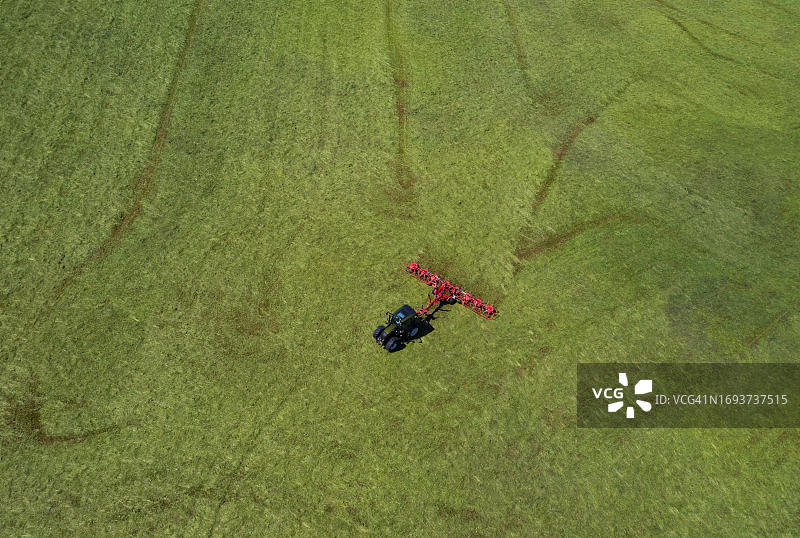 奥地利萨尔茨堡州弗拉绍地区，拖拉机在田野里翻干草航拍图片素材