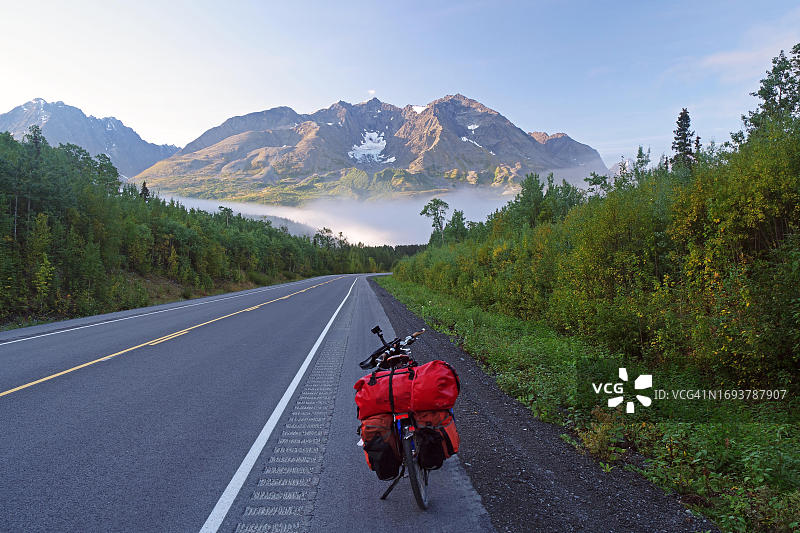 阿拉斯加理查森公路：雾中自行车，远处雪山图片素材