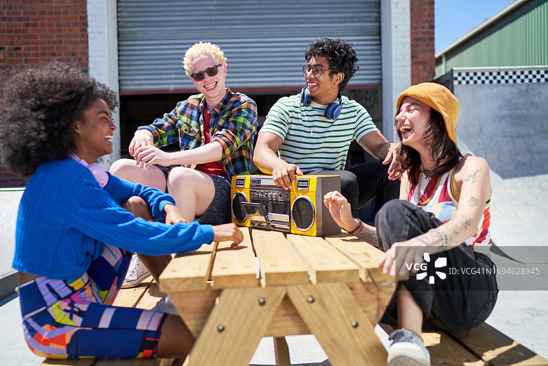 快乐的年轻朋友们一起欢笑，用手提音响听音乐图片素材