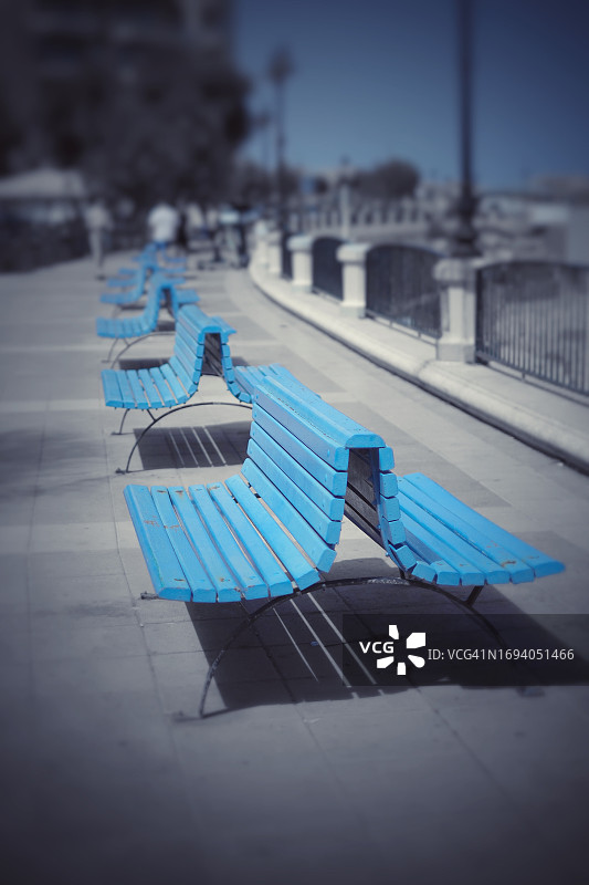 蓝色沿海步行区的彩色长椅图片素材