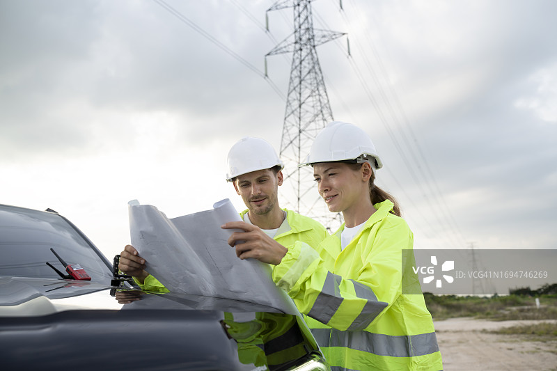 高压工程师在现场检查电力杆组件的蓝图和状况图片素材