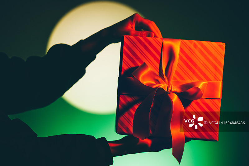女人手持圣诞礼物，背景为彩色图片素材