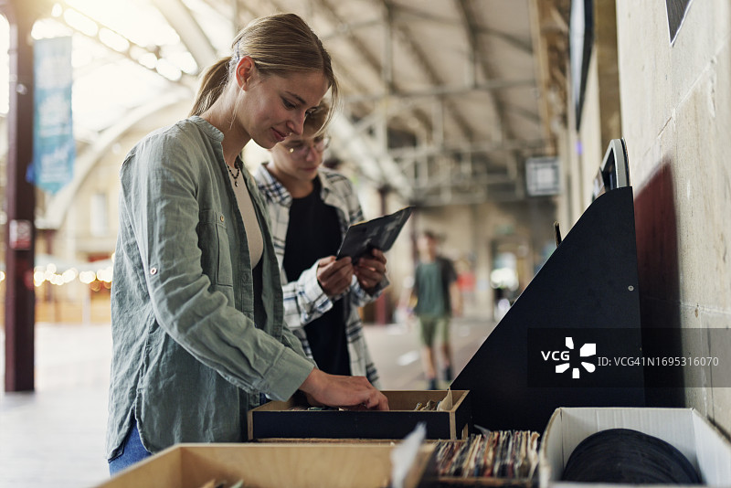 青少年在慈善商店街边摊位浏览黑胶唱片图片素材