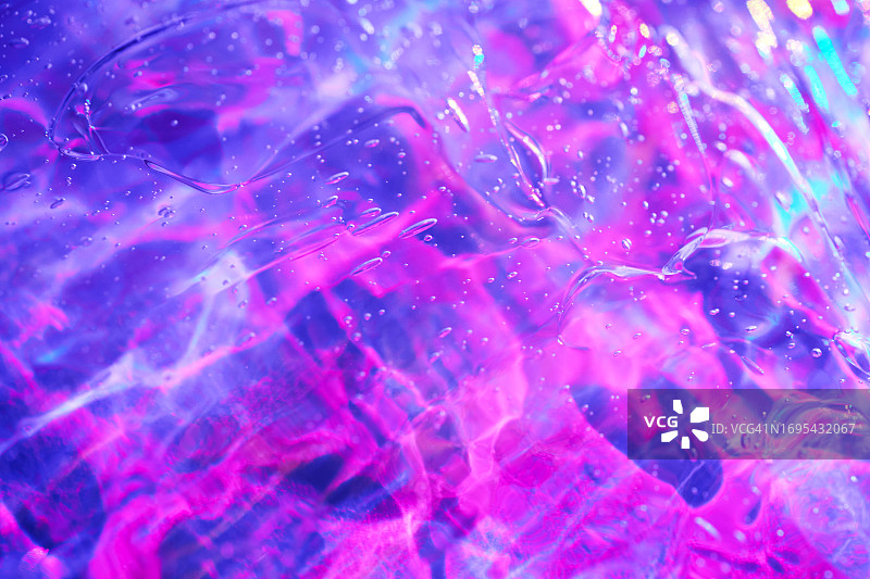 抽象全息霓虹品红色、粉色、蓝色、紫色化妆品凝胶精华背景纹理。果冻透明外星泥图片素材