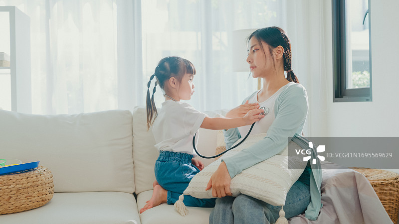 亚洲母女在家中客厅玩医生游戏图片素材