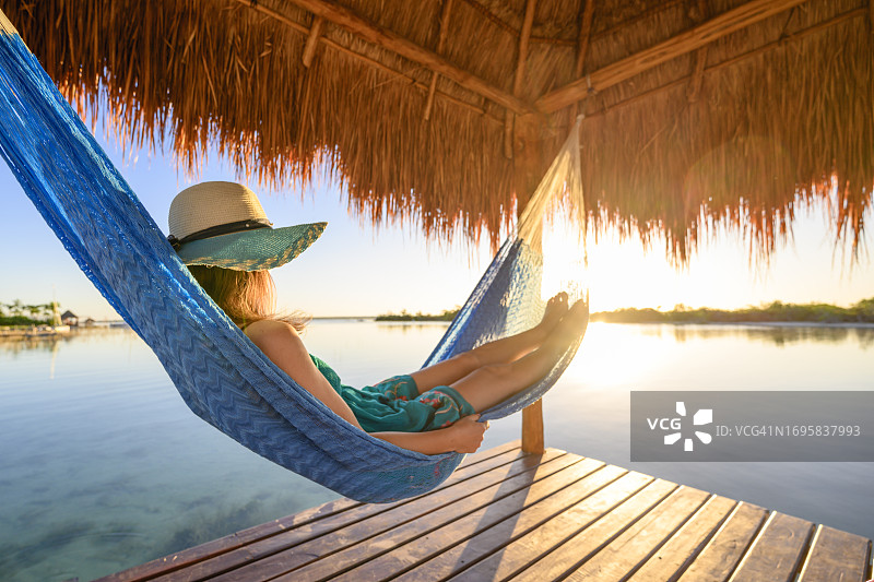 女人在墨西哥茅草屋下的吊床上放松图片素材