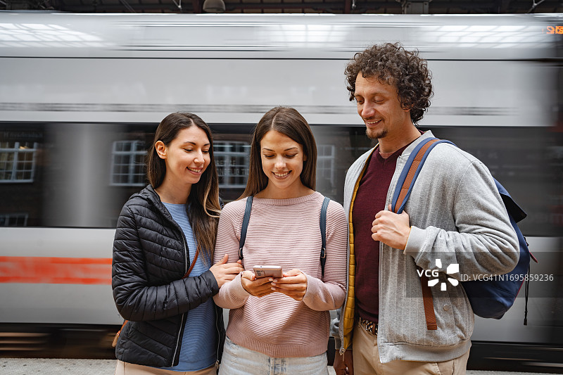 三个朋友在火车站使用手机图片素材