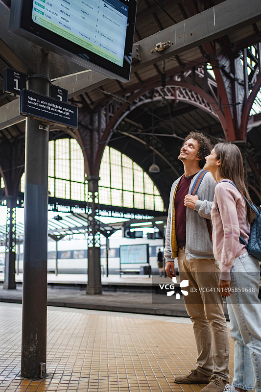 情侣在火车站看到站离站信息板图片素材