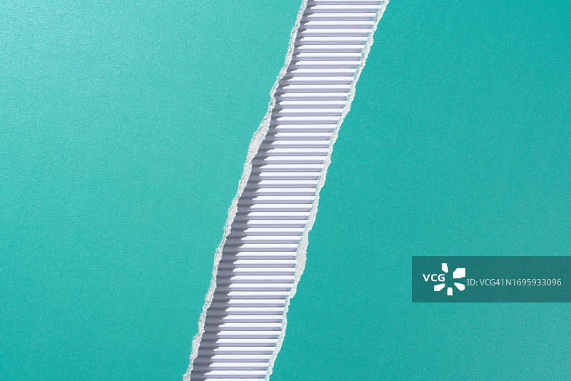 白色瓦楞纸上撕成两半的绿松石色纸张图片素材