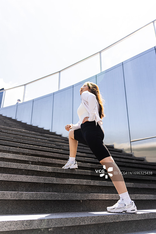 在楼梯上伸展腿部的女人图片素材