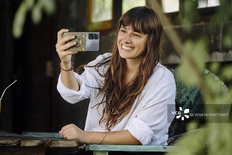 快乐的女人在热带酒吧度假村度假时用手机自拍图片素材