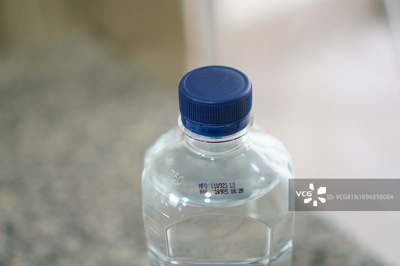 在透明塑料水瓶上盖上失效日期印章图片素材