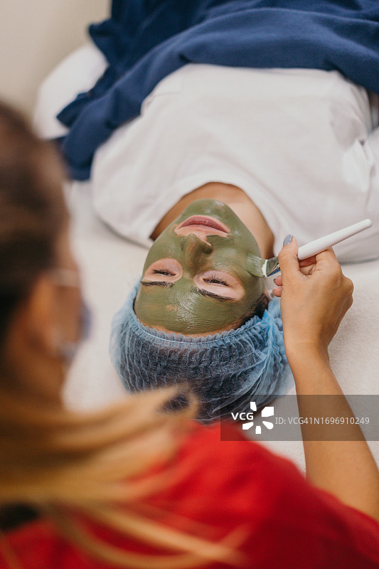 美容师为女士面部涂抹美容产品图片素材