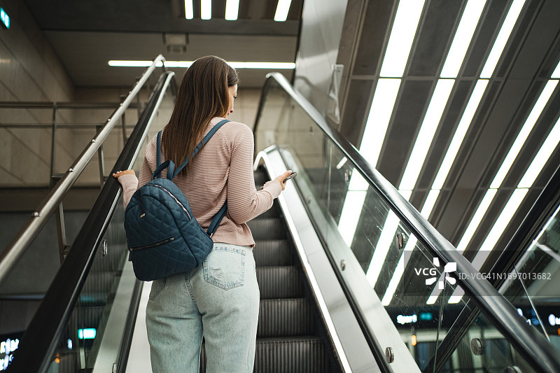 年轻女人在火车站看手机图片素材