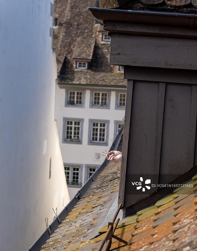 在沙夫豪森，手持香烟从屋顶窗户伸出图片素材