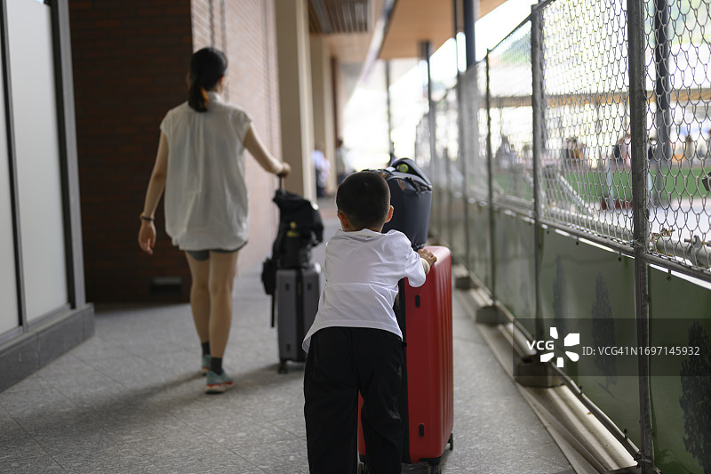 在日本长崎街头帮妈妈推行李箱的男孩图片素材