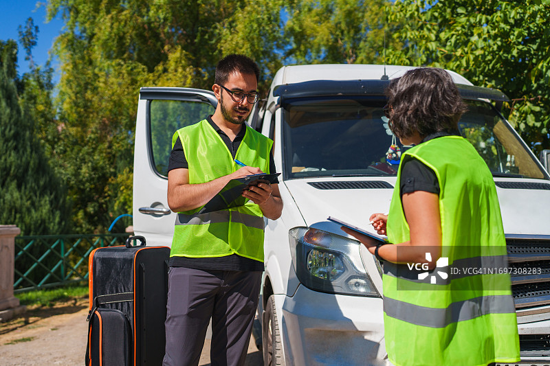 两名员工在车辆旁核对清单图片素材