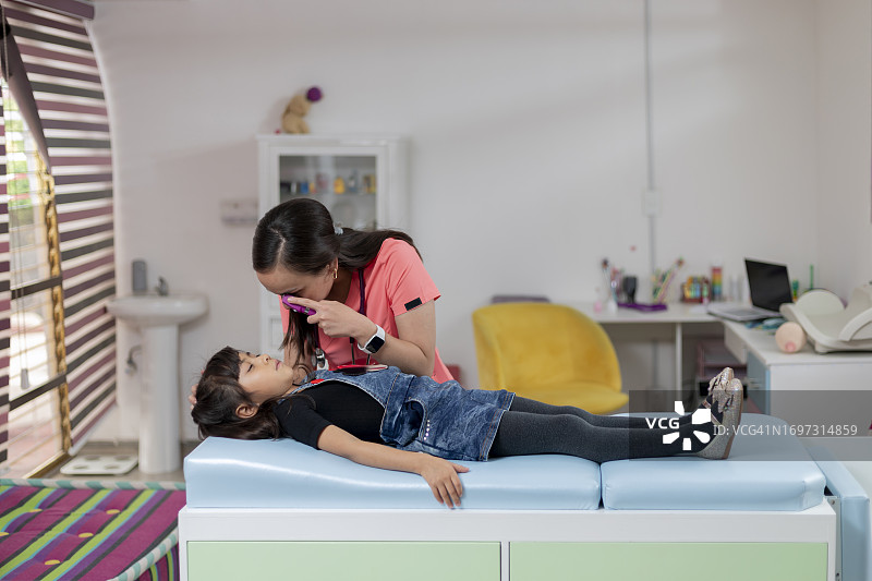 儿科医生在诊所用耳镜检查女孩的眼睛，并进行体检图片素材