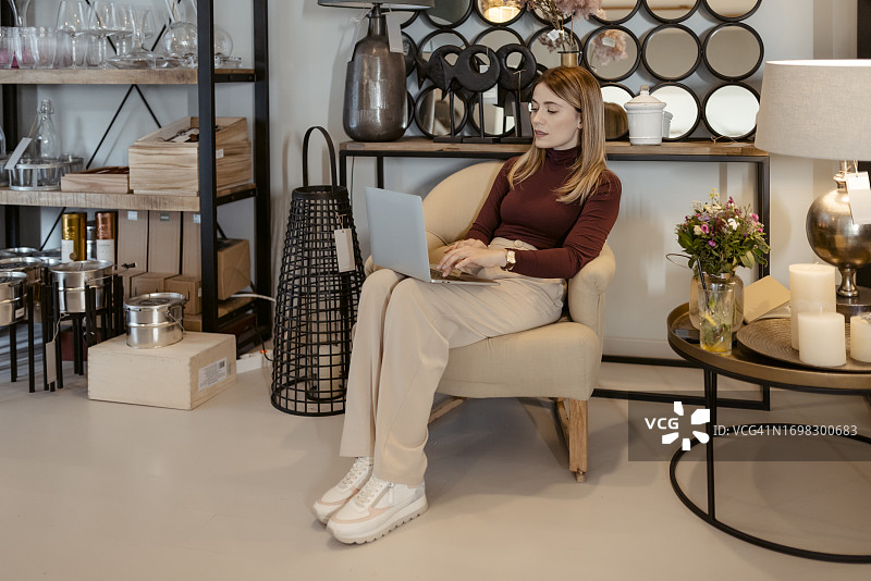 使用笔记本电脑的家居装饰店女店主图片素材