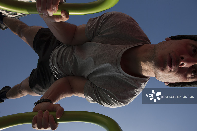 公园里青年在单杠上做体操图片素材