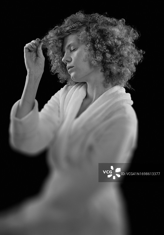 身穿白色浴袍的年轻卷发女子图片素材