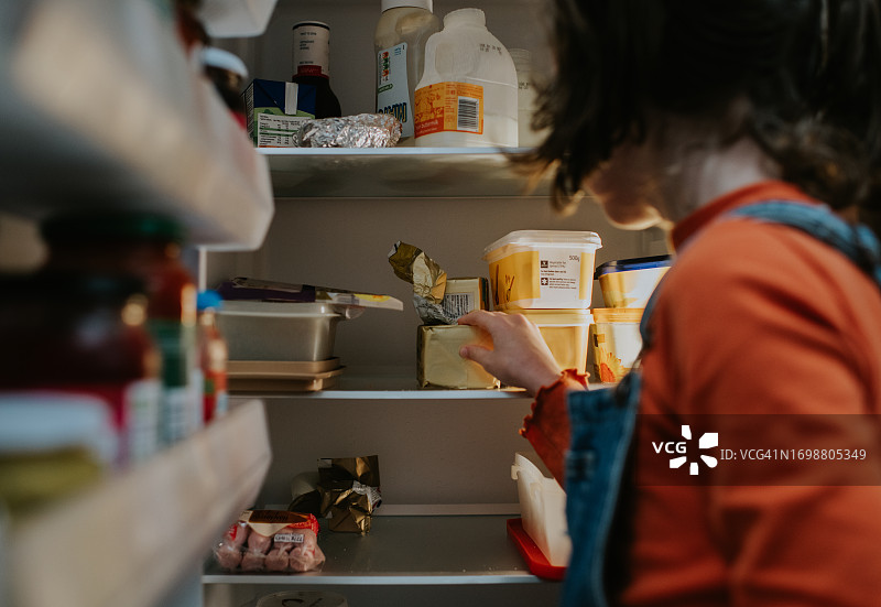 儿童伸手去拿装满食物的冰箱图片素材