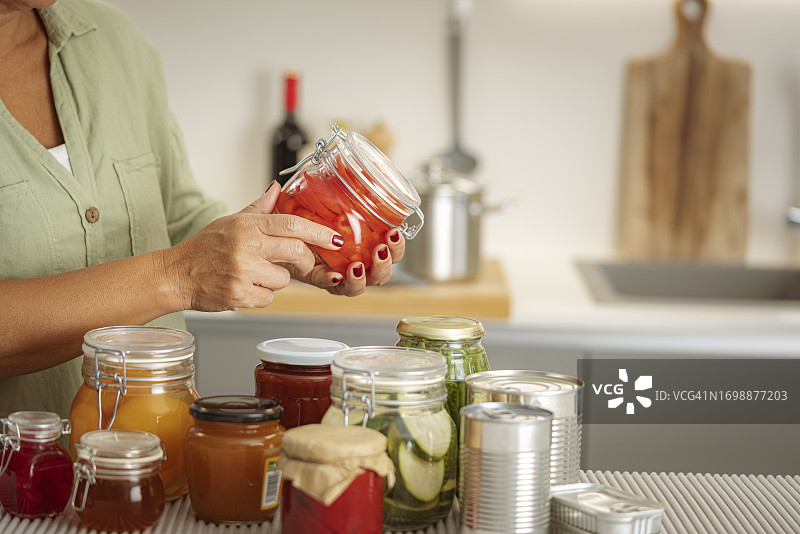 女性手持装有腌制食品的玻璃罐特写图片素材