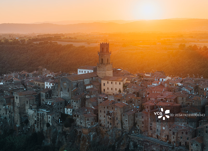 意大利托斯卡纳大区皮蒂利亚诺的圣彼得和保罗大教堂的中世纪钟楼，日落时分的航拍图片素材