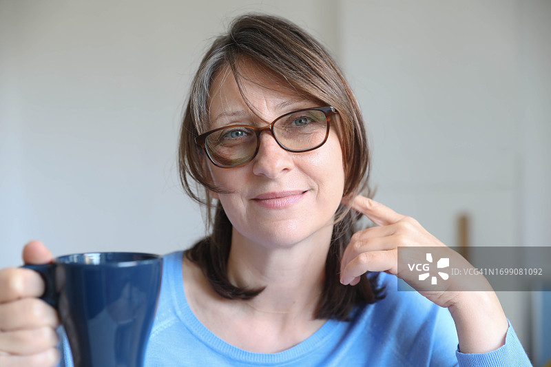 手捧茶杯沉思的中年妇女图片素材