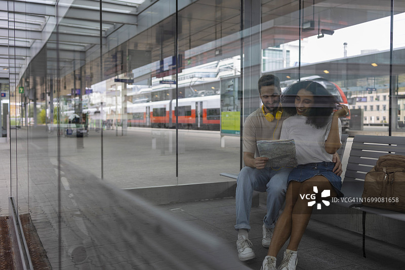 年轻情侣在火车站候车区等待列车，计划旅行图片素材