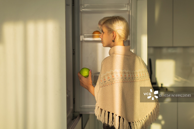 金发女人看着冰箱，早晨图片素材