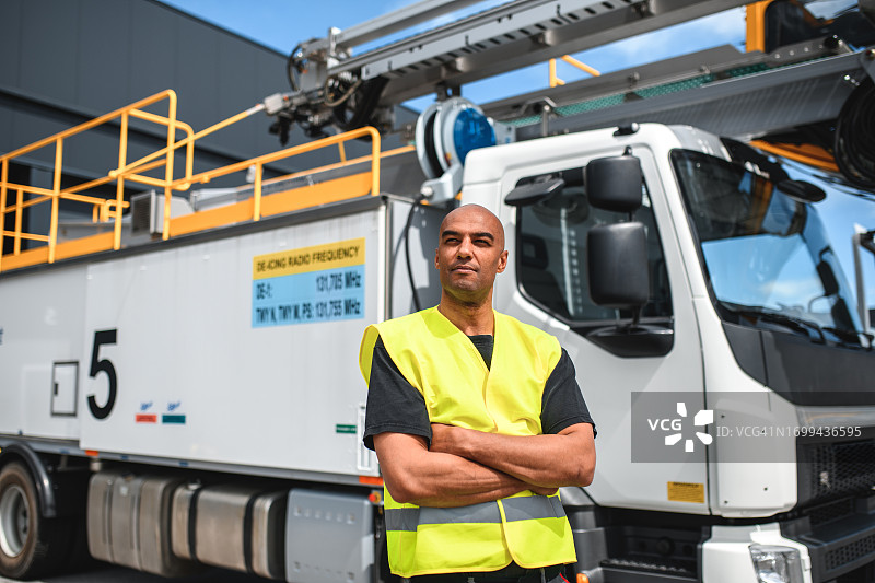 在除冰车旁的混血机场工人图片素材