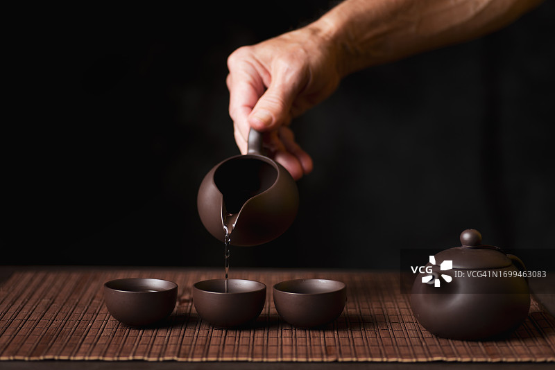 人们将茶从茶壶倒入茶杯图片素材