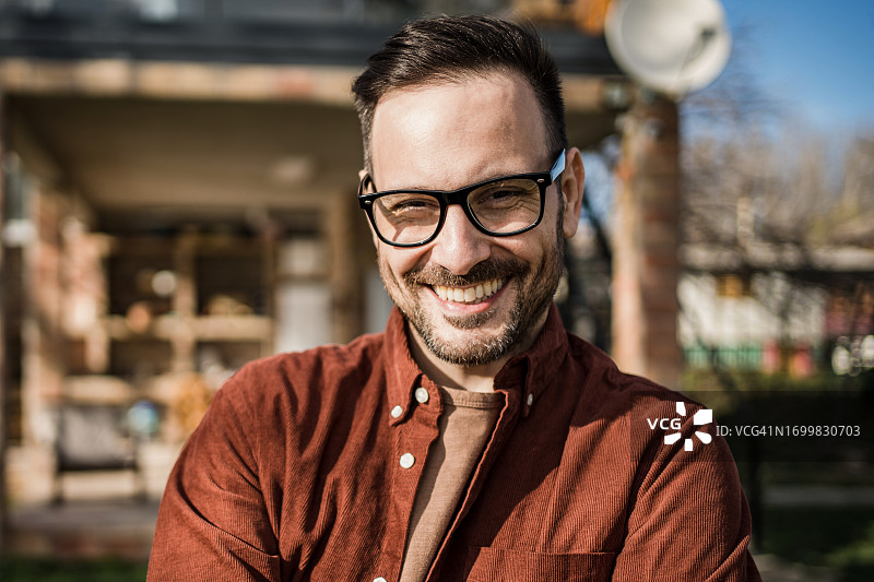 年轻男人是他身后美丽小屋的骄傲主人图片素材