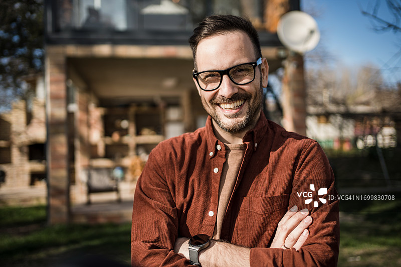 年轻男人是他身后美丽小屋的骄傲主人图片素材