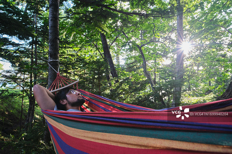 男人躺在吊床上睡觉。图片素材