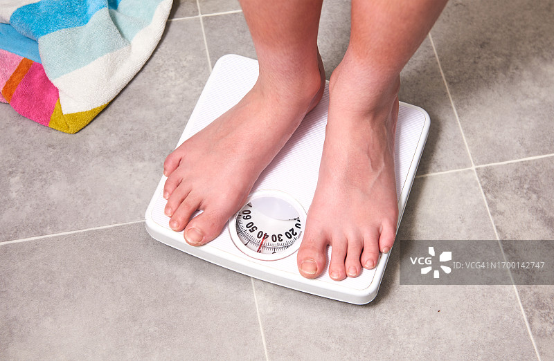 站在体重秤上的12岁男孩图片素材