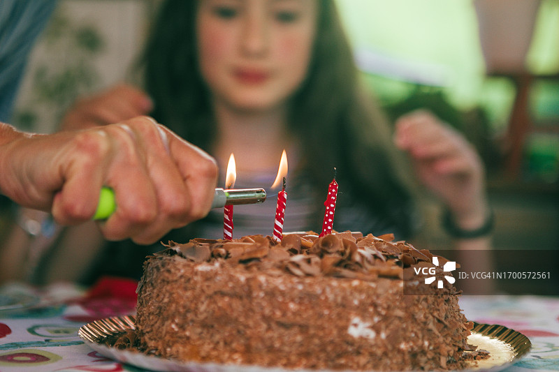 女子点燃生日蛋糕上的蜡烛图片素材