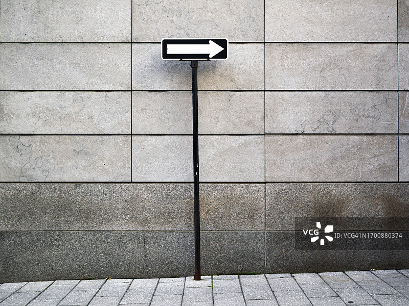 加拿大魁北克蒙特利尔的箭头路标特写，背景是灰色石墙和人行道图片素材