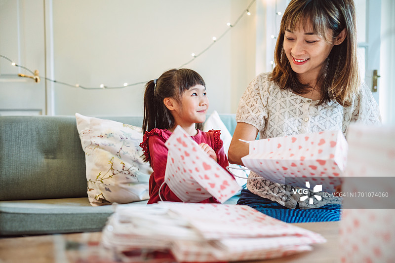 可爱的女孩和妈妈一起准备生日派对礼品袋图片素材